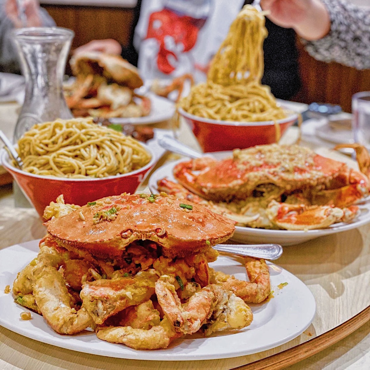 Garlic Dungeness crab with garlic noodles being served at a Bay Area restaurant — the kind of dramatic, share-ready dish that drives Instagram Story reposts and walk-in bookings.