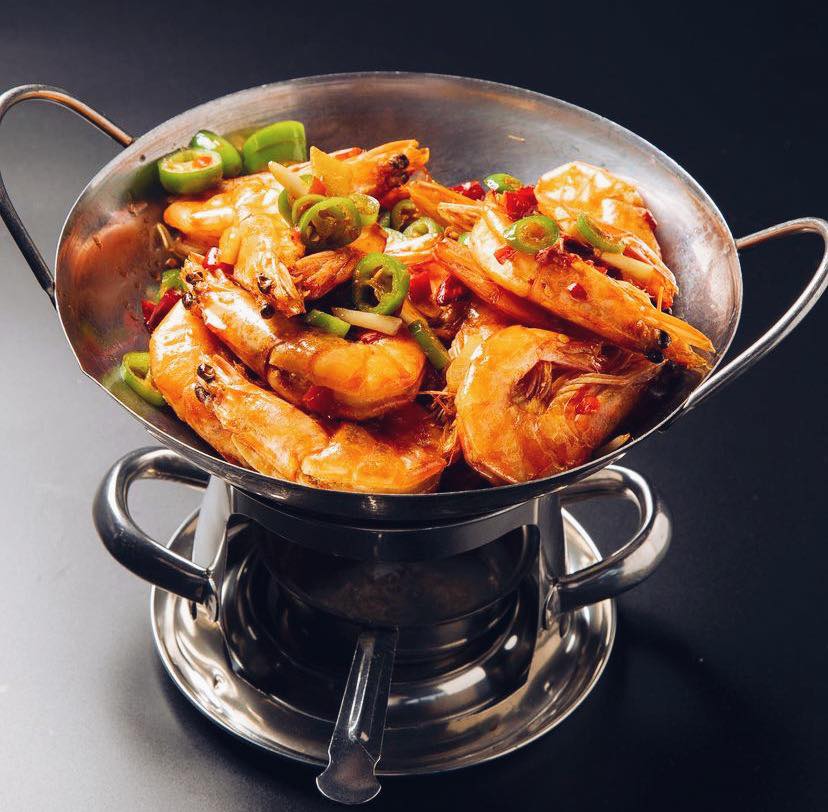Sizzling salt and pepper shrimp served in a small wok over flame at a Bay Area restaurant — an example of the high-contrast, scroll-stopping food photography this guide teaches.