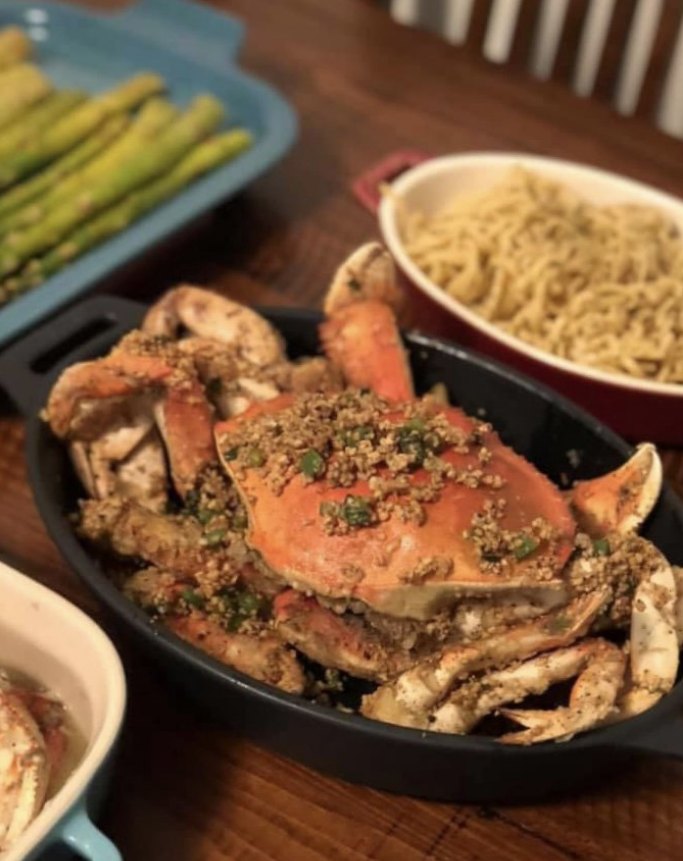 Whole black peppercorn Dungeness crab over garlic noodles in a cast-iron skillet at a Bay Area restaurant — the kind of signature dish that brings regulars back.