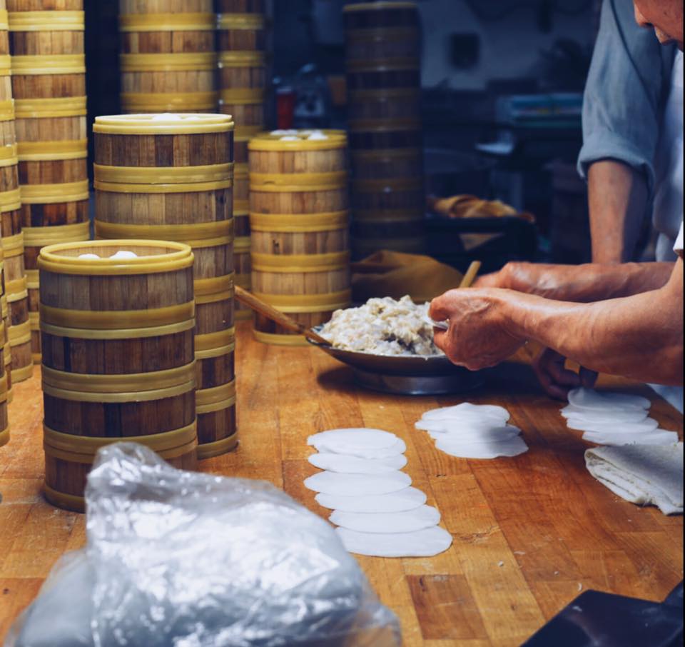 A cook’s hands shaping dim sum dough beside stacks of bamboo steamers in a South San Francisco restaurant kitchen, the kind of behind the scenes moment that makes strong restaurant social media content.