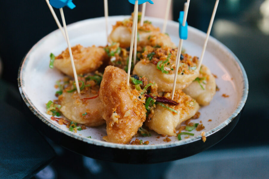 A plate of golden crispy fried wontons topped with fried garlic, scallions and dried chili, served with bamboo picks at a Bay Area restaurant, the kind of shared appetizer a fully staffed kitchen sends out on an ordinary service.