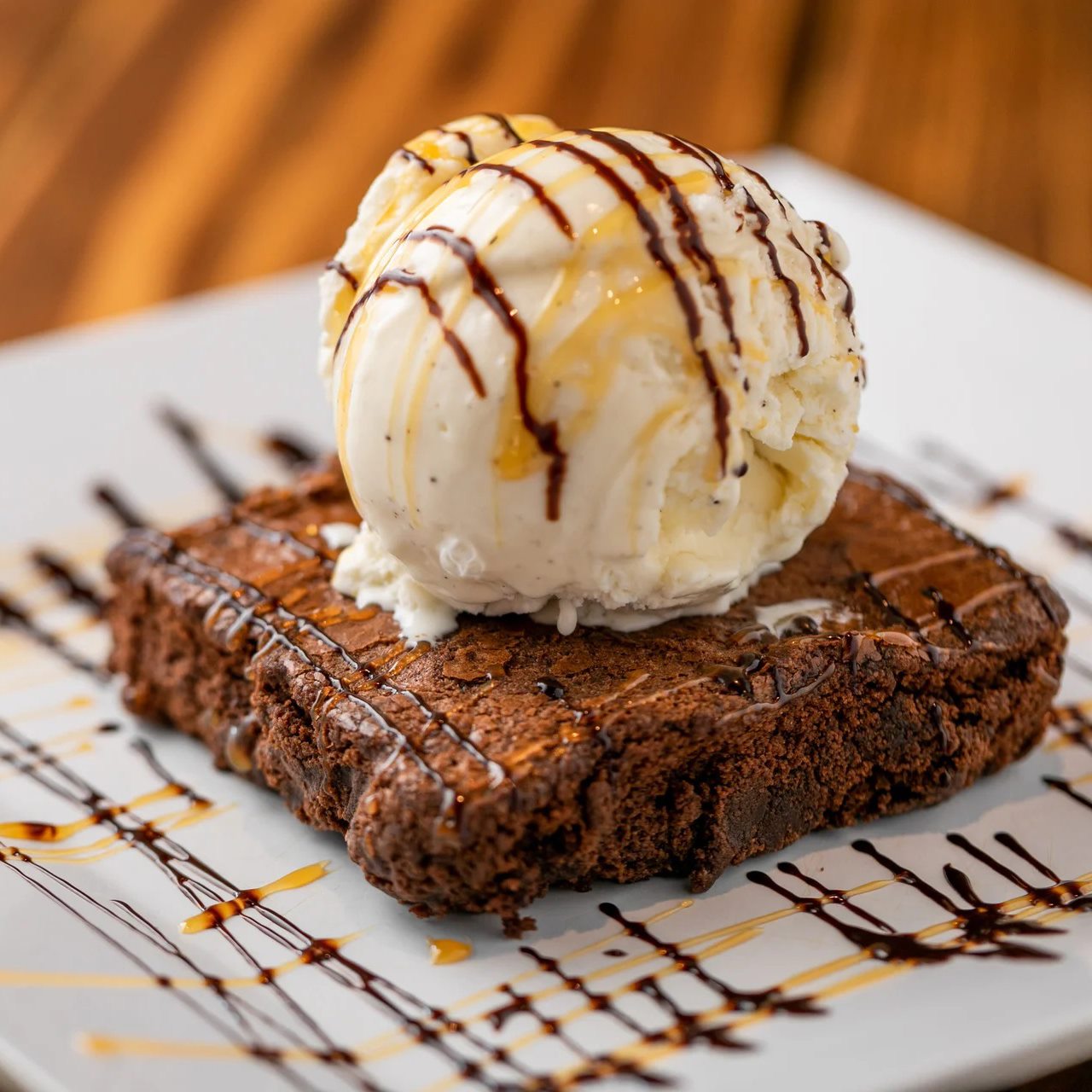 A warm chocolate brownie topped with a scoop of vanilla bean ice cream and drizzled with chocolate and caramel, the kind of on-the-house surprise that turns a Bay Area restaurant’s first-time guests into loyal regulars.